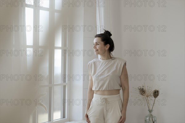 Dark-haired woman stands relaxed at the window