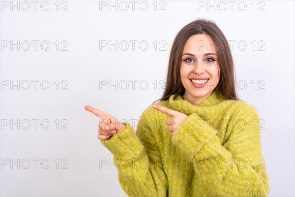 Attractive woman smiling pointing fingers at copy space on white background