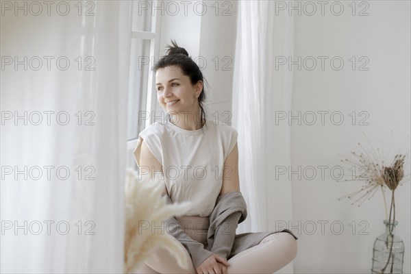 Dark-haired woman sits relaxed at the window