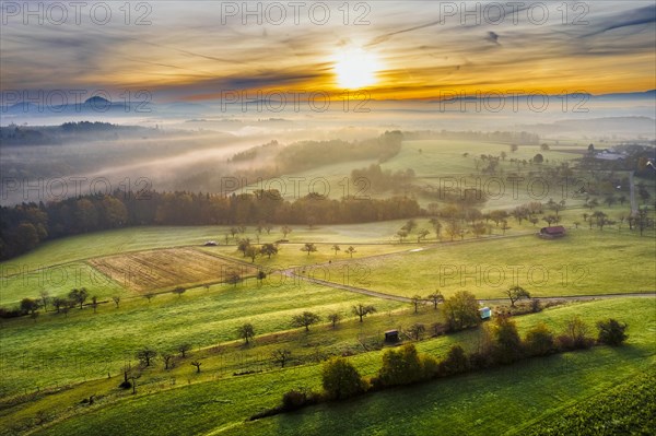 Drone view of sunrise over forest and rural landscape in autumn