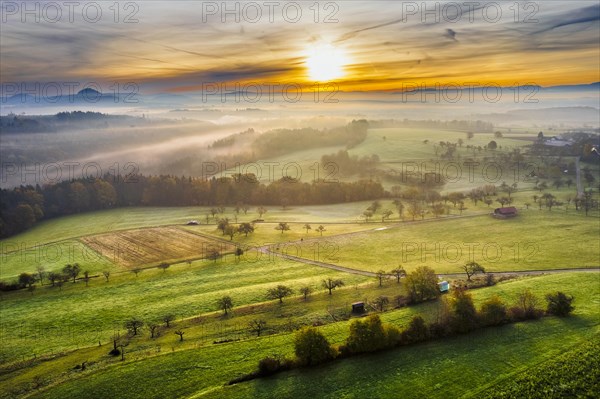 Drone view of sunrise over forest and rural landscape in autumn