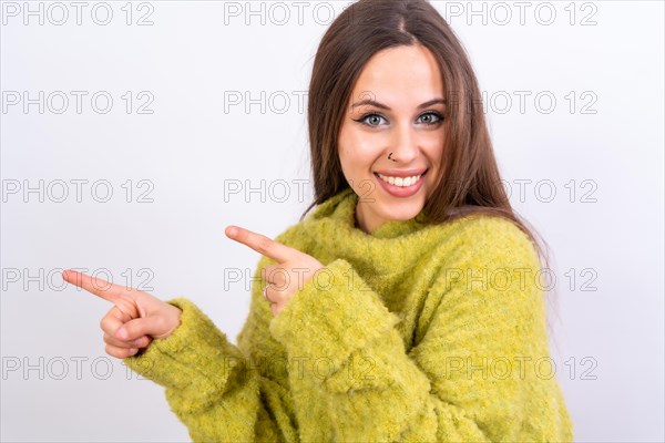 Attractive woman smiling pointing fingers at copy space on white background