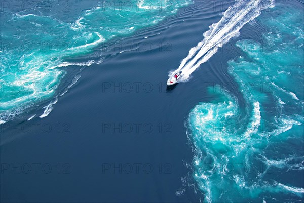 Powerboat between huge whirlpools and eddies in the water of a fjord