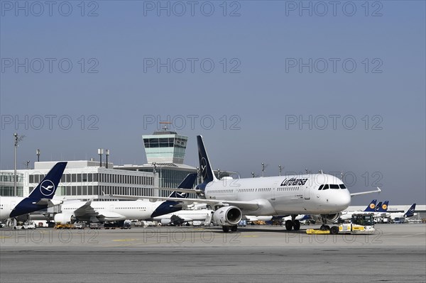 Lufthansa aircraft Airbus A321-200 with push-back truck in front of satellite