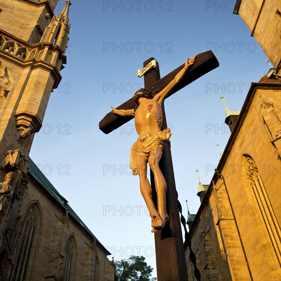 Jesus Christ on the cross between Erfurt Cathedral and Severi Church in early morning light