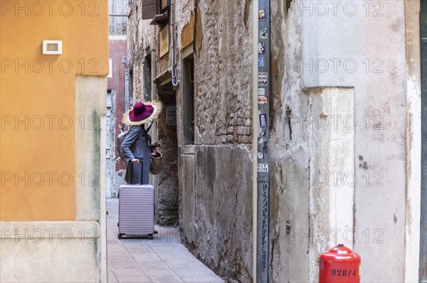 Young woman with suitcase in the alleys of Venice