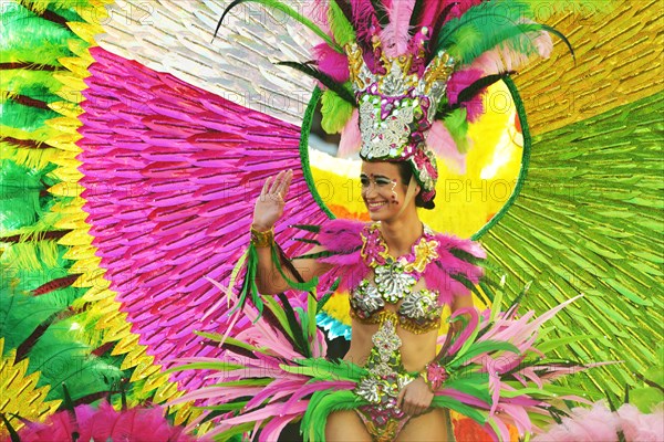 Multicoloured people of all ages praise the parade in Carnival