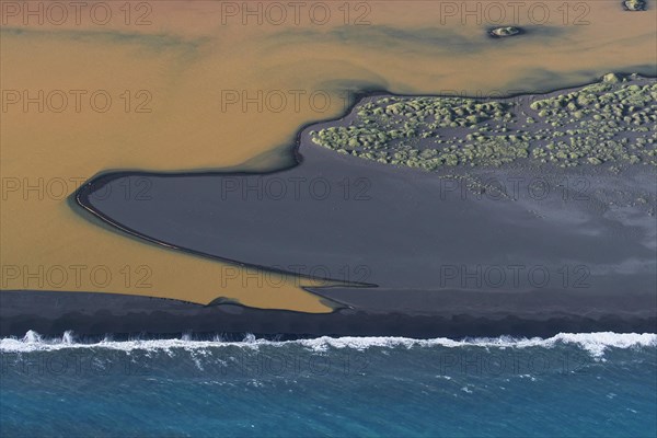 Aerial view over Landeyjarsandur showing beach with black volcanic sand and brown water laden with sediment flowing in sea in summer