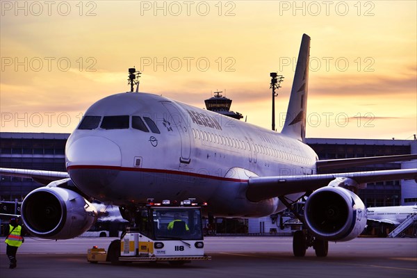 Agean Airlines aircraft towing in front of Terminal 2 in the sunset