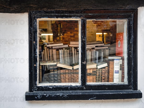 View through an old window on stacks of books