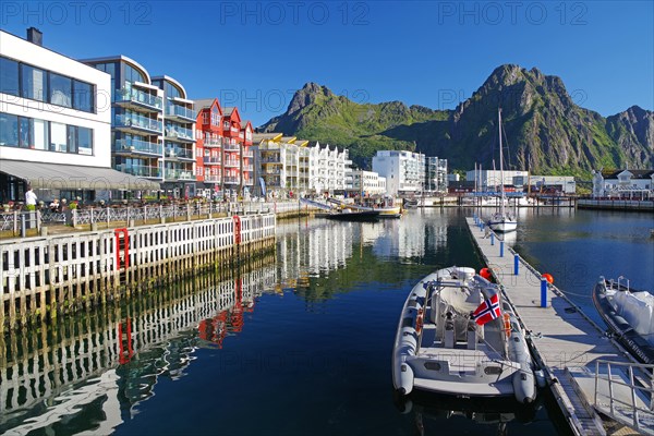 Modern houses reflected in the calm waters of the small harbour of Svolvaer