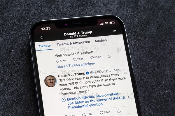 Smartphone with a Twitter tweet from Donald Trump with a message about his conspiracy theories