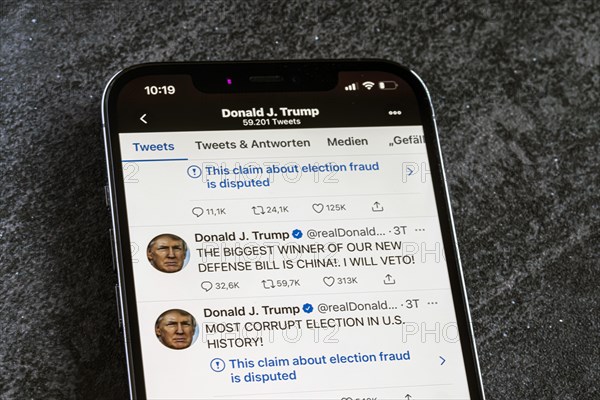 Smartphone with a Twitter tweet from Donald Trump with a message about his conspiracy theories