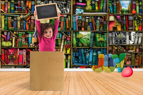 Child in a box holding up a blackboard