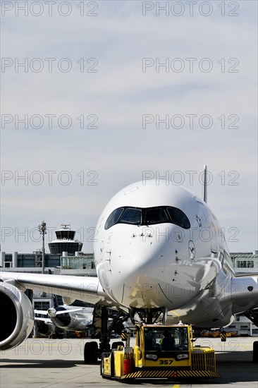 Lufthansa Airbus A350-900 towing with push-back truck in front of Terminal 2 with tower