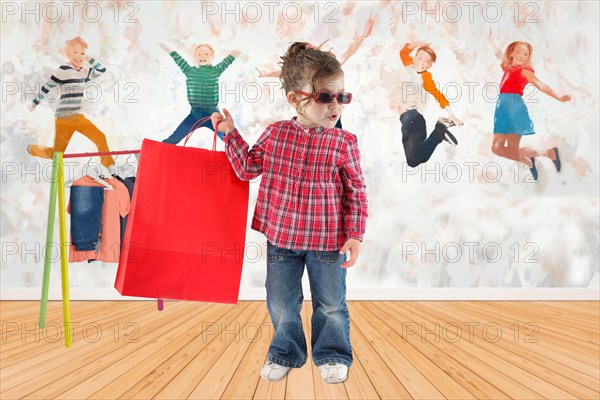 Child in the childrens room holding a shopping bag with new clothes in her hand