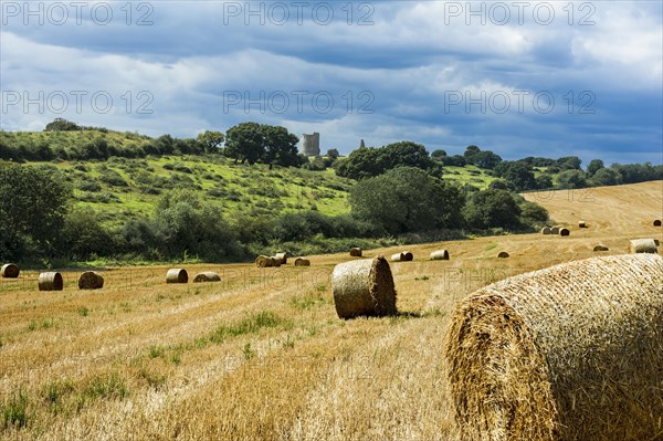 Storm clouds building over recently harvested straw bales. Concept for dangers and threats to the farming industry