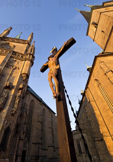 Jesus Christ on the cross between Erfurt Cathedral and Severi Church in early morning light