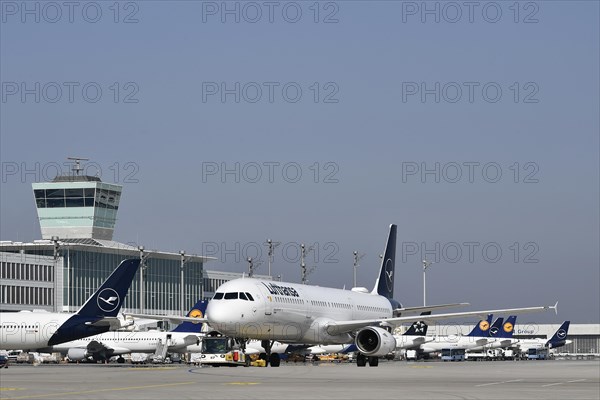 Lufthansa aircraft Airbus A321-200 with push-back truck in front of satellite