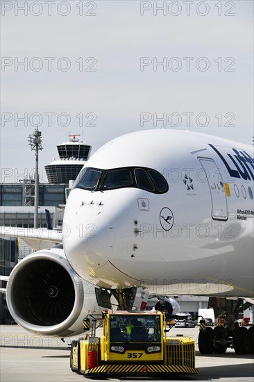 Lufthansa Airbus A350-900 towing with push-back truck in front of Terminal 2 with tower