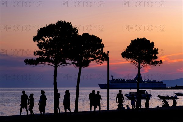 Tourists walking on promenade and cruise ship moored in the Bay of Vlore