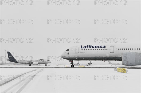 Aircraft taxiing on taxiway in winter snow flurry for de-icing and take-off clearance