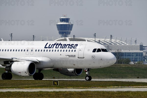 Lufthansa Airbus A320-200 taxiing on runway north with tower in the background