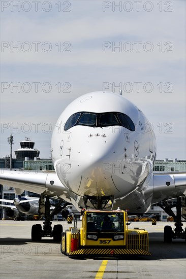 Lufthansa Airbus A350-900 towing with push-back truck in front of Terminal 2 with tower