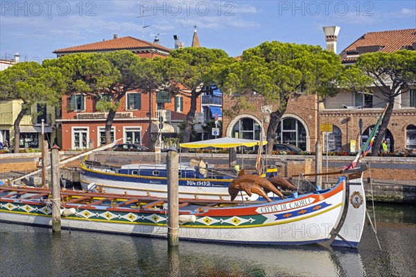 Traditional wooden boat docked in canal in the city Caorle