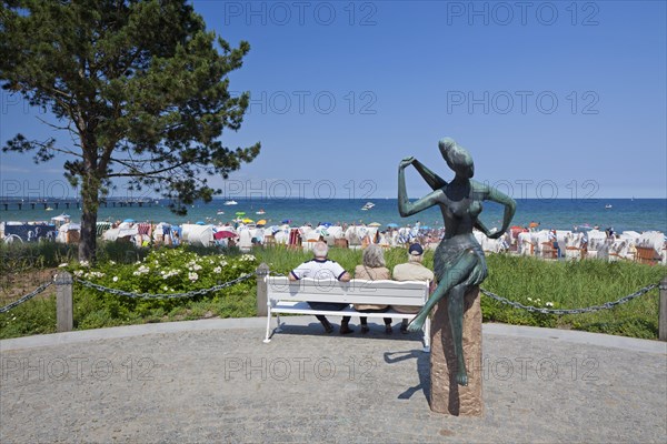 Tourists sitting on bench and looking over the beach at Timmendorfer Strand