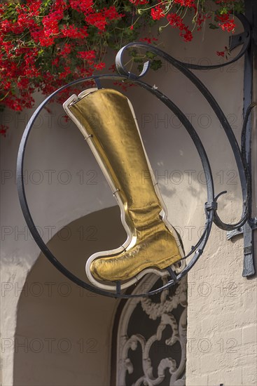 Gold-coloured boot as nose sign of a shoe shop