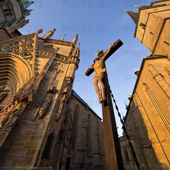 Jesus Christ on the cross between Erfurt Cathedral and Severi Church in early morning light