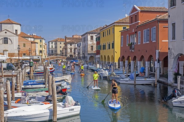 Tourists standup paddleboarding on canal Vena at Chioggia