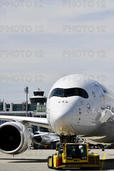 Lufthansa Airbus A350-900 towing with push-back truck in front of Terminal 2 with tower