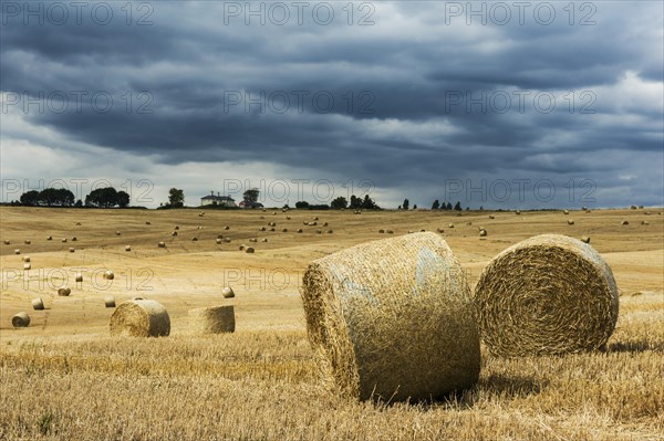 Storm clouds building over recently harvested straw bales. Concept for dangers and threats to the farming industry