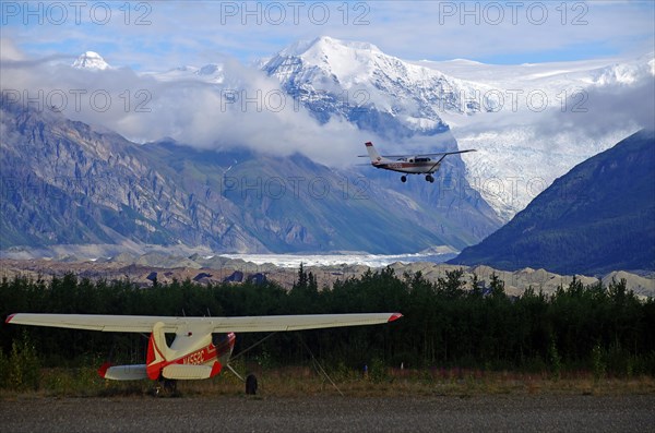 Two small bush planes in front of huge glaciers