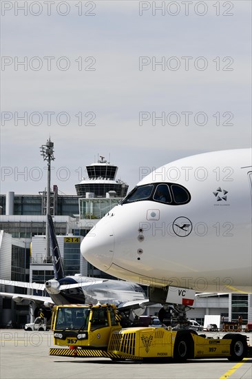 Lufthansa Airbus A350-900 towing with push-back truck in front of Terminal 2 with tower