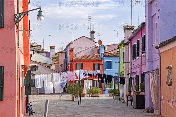 Laundry hanging to dry in alley with brightly coloured houses at Burano