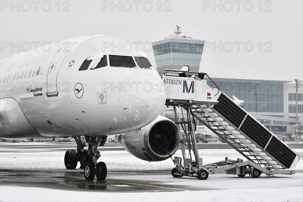 Lufthansa Airbus A319-100 in winter with snow with electric solar-powered passenger boarding bridge