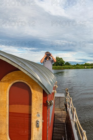 Man With Binoculars on a House Raft, Pension Havelfloss, Brandenburg an der Havel, Havelland, Brandenburg, Germany, Europe