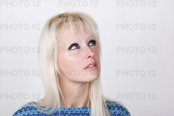 Portrait of young blond woman thinking and looking somewhere up