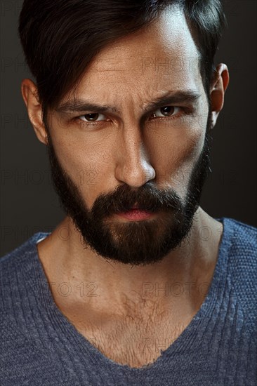 Closeup portrait of serious man with beard and mustache looking straight severe