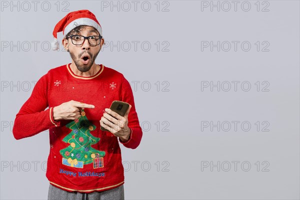 Amazed man pointing at christmas offer online, Guy pointing at christmas promotion on phone. Online Christmas special offers concept, amazed people pointing at a Christmas promotion on phone