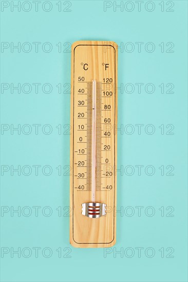 Wooden thermometer on green background