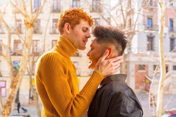 Beautiful gay couple being romantic at home on the sofa, home balcony kissing each other on the forehead, lgbt concept