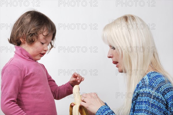 Mom giving a banana to his daughter