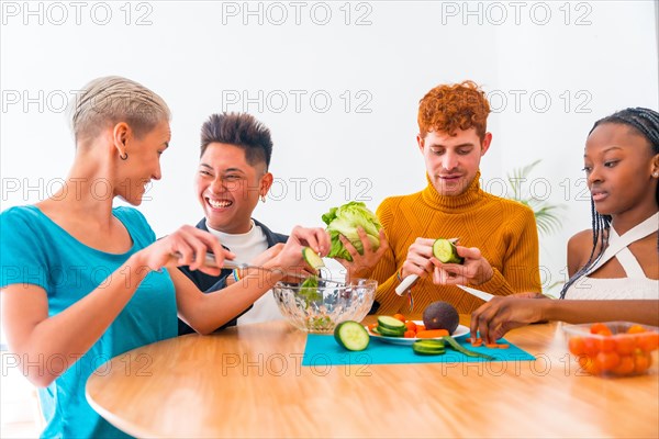 Group of friends preparing a salad. They prepare food and have fun in the kitchen