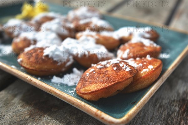 Poffertjes, a traditional Dutch batter treat dish resembling small, fluffy pancakes, served with powdered sugar and butter