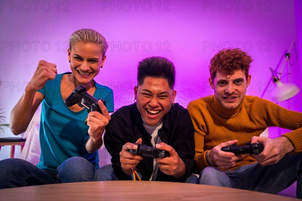 Group of young friends playing video games together on the sofa at home, competing looking at camera