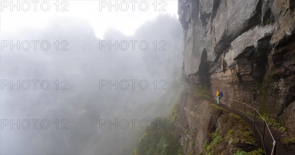 Hiker in the fog, Pico Arieiro to Pico Ruivo hike, hiking trail at rock cliff, Central Mountains of Madeira, Madeira, Portugal, Europe